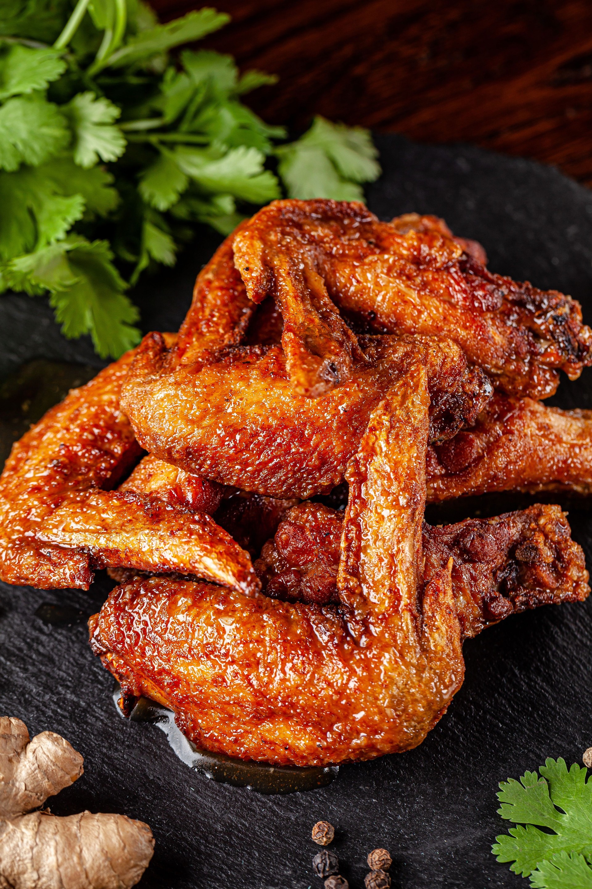 American cuisine. Fried chicken wings glazed in marinated with ginger and garlic on a black background. background image, copy space text.