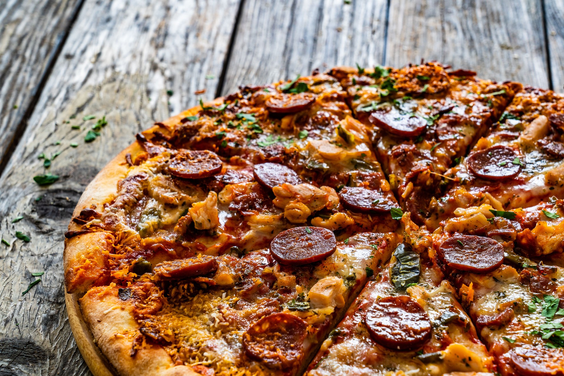 Circle pizza chorizo with chicken nuggets and mozzarella, on wooden table