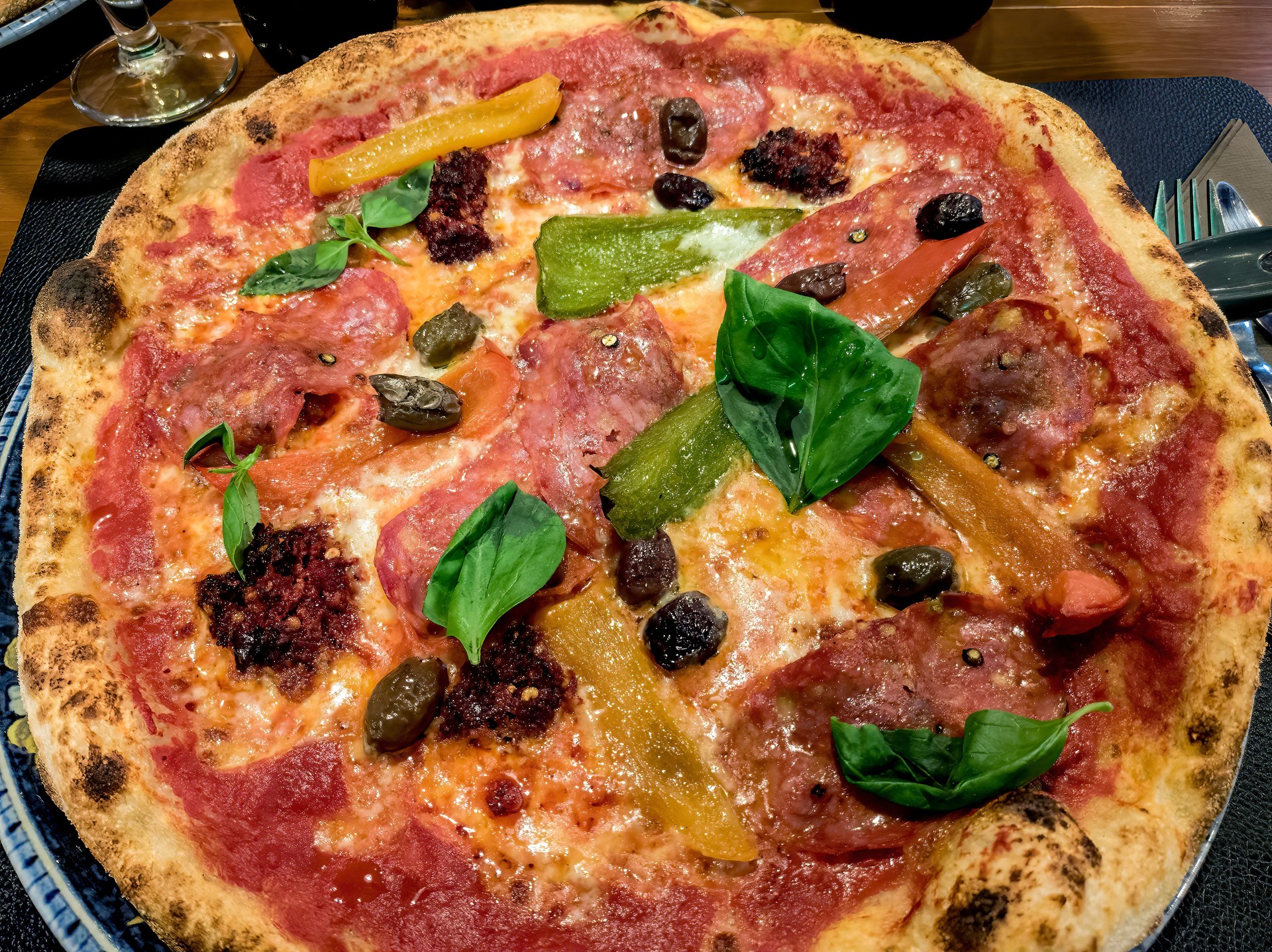 Pizza with salami, pepper, basil and olives