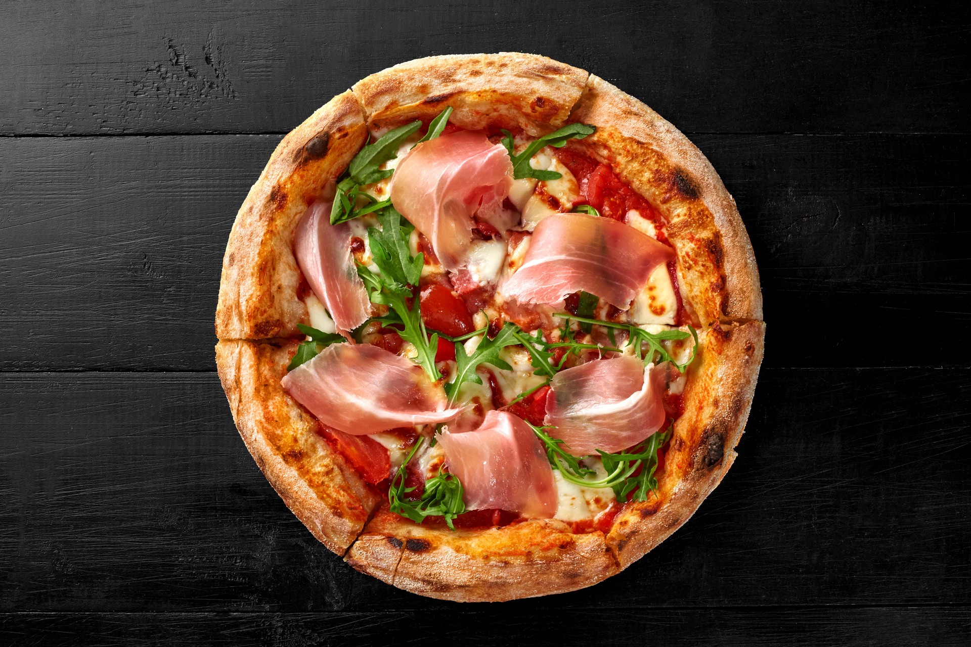 Pizza with salami, prosciutto, tomatoes, mozzarella and fresh arugula