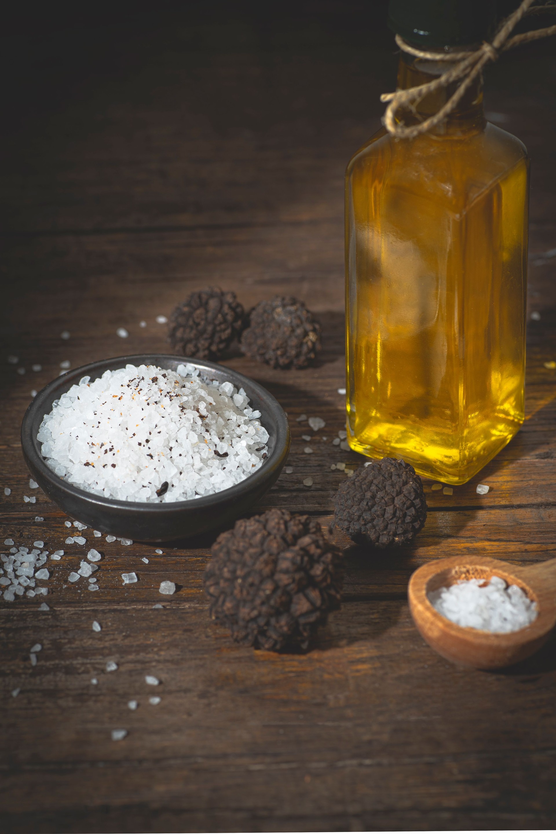 Truffle salt and truffle oil on a rustic wooden table, how to preserve the aroma and taste of black truffle. Preserving black truffle. Atmospheric still life in the style of a chef's table, front view